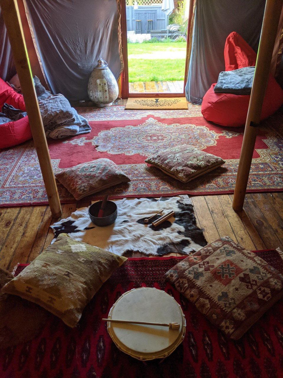 Inside of a tent with rugs, drums and cushions laid out on the floor